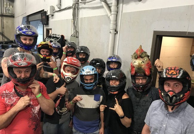 Groupe de personnes portant des casques de karting dans un garage, prêtes pour une activité d'esprit d'équipe.