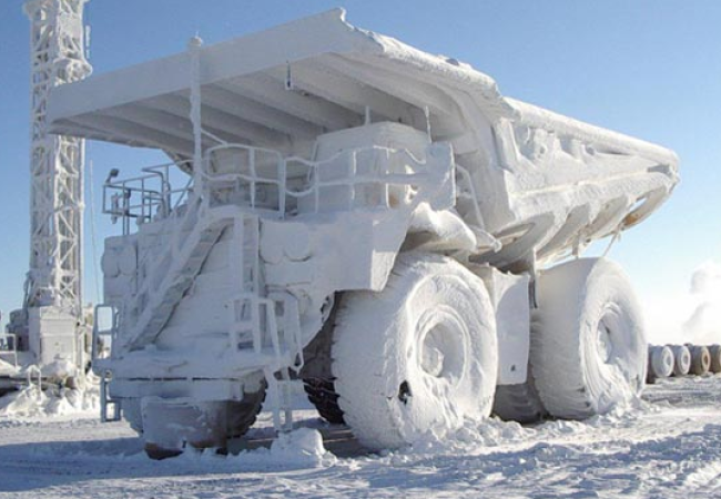 Camion minier lourd couvert de neige et de glace dans un paysage hivernal en plein air.