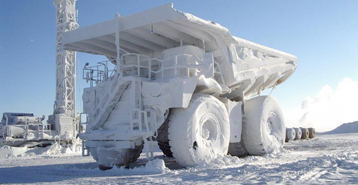 Camion minier lourd couvert de neige et de glace dans un paysage hivernal en plein air.